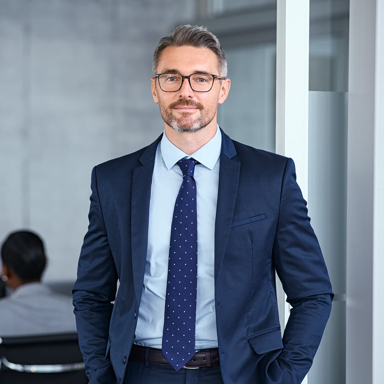 A person working on a laptop at a desk with a plant in the foreground
